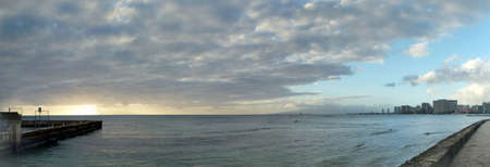 Panoramic of Waikiki Sunset over the ocean with clouds in the air and hotels in tghe distance on Oahu, Hawaii.の写真素材