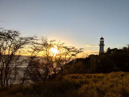 Sunset over the ocean and Diamond Head Lighthouse on Oahu.  Diamond Head Lighthouse is a United States Coast Guard facility located on Diamond Head in Honolulu, on the island of OÊ»ahu in the State of HawaiÊ»i. The lighthouse was listed on the National Register of Historic Places in 1980.の写真素材