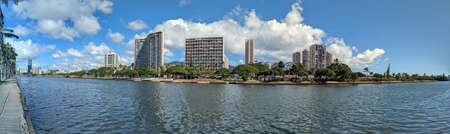 Waikiki - February 28, 2022: Ala Wai Canal, Condos, Golf Course and Coconut trees on a nice day on Oahu, Hawaii with mountains in the distance. Panoramic style.のeditorial素材