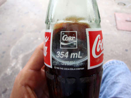 San Jose, Costa Rica - July 13, 2009: Close-up of Hand holding 
glass Coke Bottle 354ml made in 1995.のeditorial素材