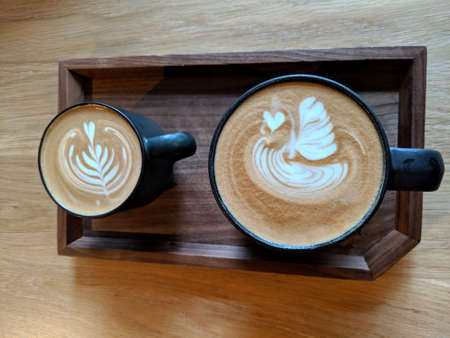 Cappuccino with Swan and expresso heart leaf on wood plate.