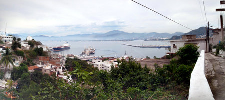 Mexico - January 11, 2010: Manzanillo City, streets, and Harbor seen from the hills with several cargo ship and boating vehicles on an overcast day.  Panoramic.の写真素材