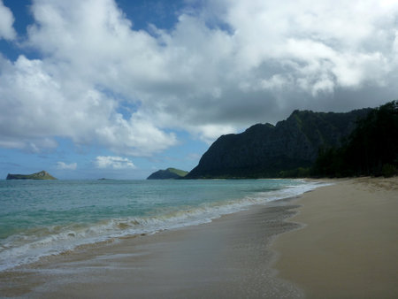 Gentle wave lap on Waimanalo Beach looking towards Rabbit island and Rock island on a nice day with clouds in the sky on Oahu, Hawaii.の写真素材