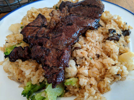 Fried rice with Kalbi Steak on top on plate on table.の写真素材