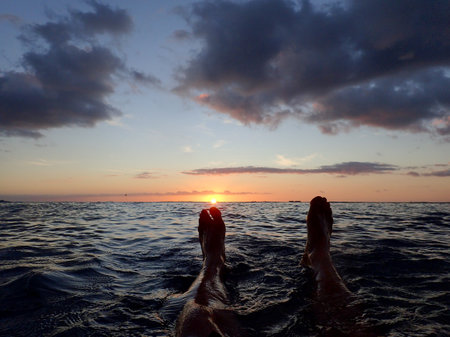 Feet enjoy the view of a Waikiki Sunset from above the water on Oahu, Hawaii.の写真素材