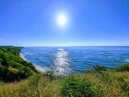 The sun rises over Diamond Head Beach, casting a golden glow over the ocean. The waves crash against the shore, and the seagulls soar overhead. It's a beautiful morning to be at the beach.の写真素材