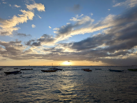 A group of boats floating on top of a body of water at Sunset in Waikiki, Hawaiiの写真素材