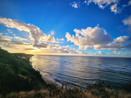 As the sun ascends above the horizon, its warm rays embrace the rugged silhouette of Diamond Head, casting a golden glow upon the tranquil waters of Oahu. The sky transitions from deep blues to soft pastels, creating a breathtaking canvas that captivates both early risers and nature enthusiasts alike.の写真素材