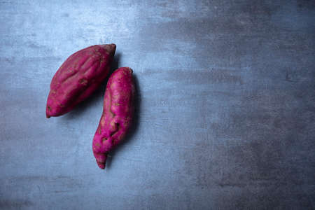 raw sweet potato on gray stone, view from above, free spaceの写真素材