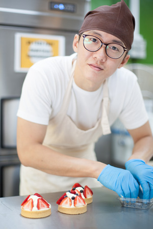 Asian Baker making strawberry shortcakeの写真素材