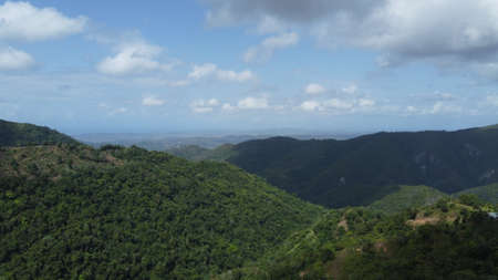 Aerial view of green mountain range and blue sky with white clouds