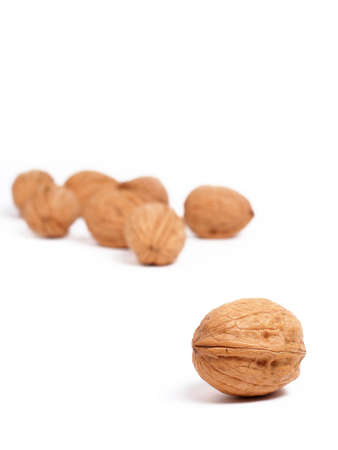 A single walnut in focus and several out-of-focus walnuts in the backgroundの写真素材