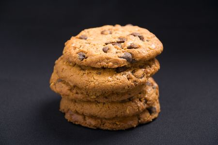 A stack of hazelnut and chocolate chips cookies on a dark background