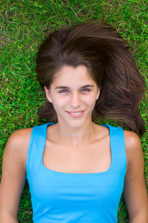 Cute young woman lying on grass in the parkの写真素材