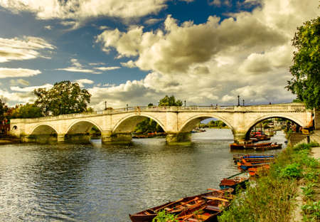 Richmond Bridge spanning over the river Thames and rowing boats in summer on a overcast day, Londonの写真素材