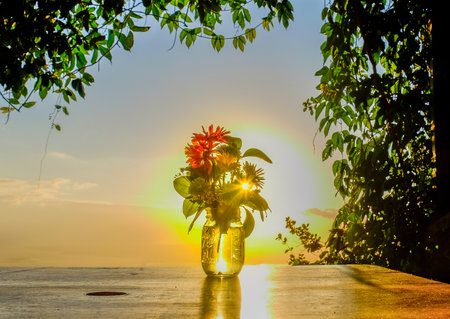 Flowers in a glass jar facing the sunset over the Blue Mountains, Jamaica
