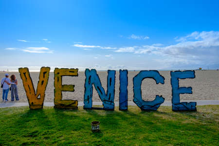 California, U.S.A, March 2019, a couple on a beach standing by a "Venice" sign on Venice Beach Ocean Front Walkのeditorial素材