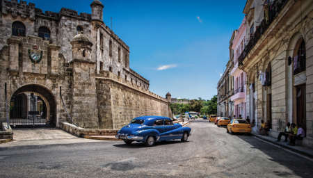 Havana, Cuba, July 2019, blue Chevrolet driving pass the police headquarters in the old cityのeditorial素材