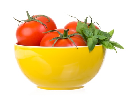 Tomatoes and basil in yellow bowl isolated on white backgroundの写真素材