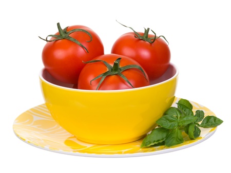 Tomatoes and basil in yellow bowl and plate isolated on white backgroundの写真素材