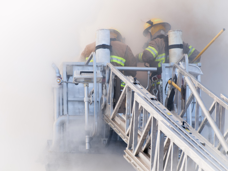 Firefighters on platform sky jack in heavy grey smokeの写真素材