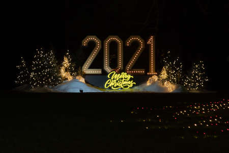 During a snowy winter evening a festive illuminated sign displays the message, "2021- Merry Christmas."の写真素材