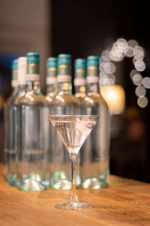A cold martini is served in a cocktail glass and presented in front of several generic unlabelled bottles.の写真素材