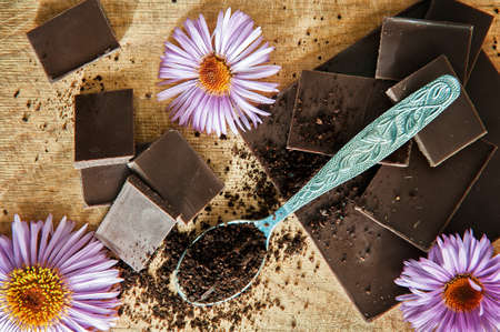 Dark chocolate stack, chips and powder. Chocolate and flowers. Chocolate slices decorated beautiful...