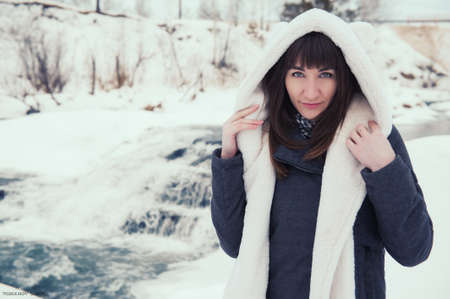 Girl near the winter waterfall. Winter river.の写真素材