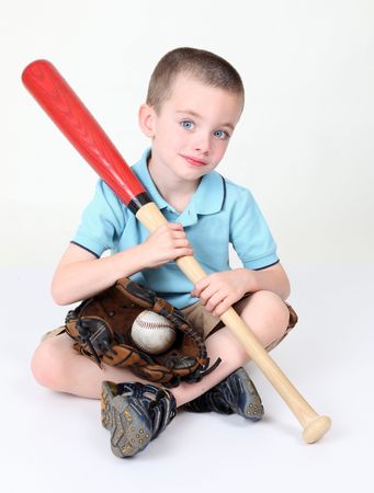 Preschool boy sitting down holding bat in studioの写真素材