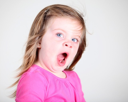 Tired toddler girl yawning on light backgroundの写真素材