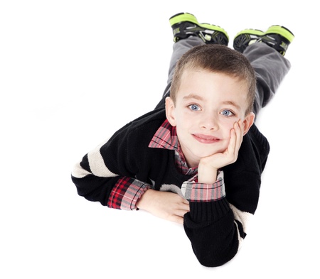 Young boy laying on stomach with chin resting in hand in studio isolated on whiteの写真素材