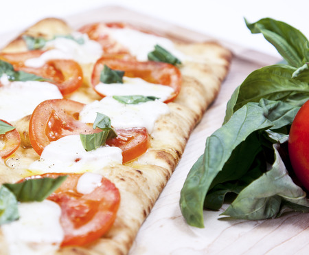 Fresh pizza with tomato, mozzarella and basil on wooden boardの写真素材
