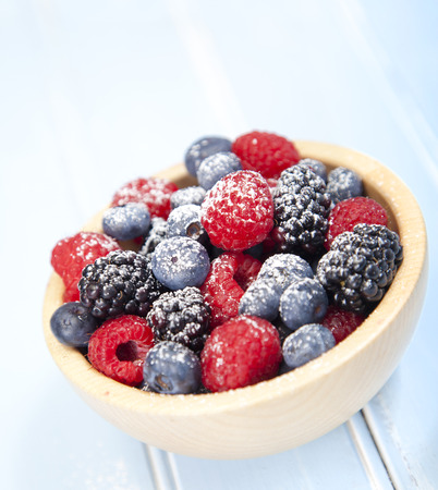 Assorted mixed berries in a bowl on wooden backgroundの写真素材