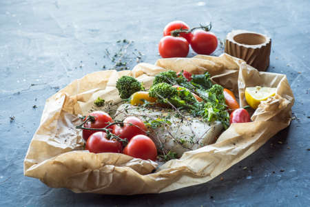 Raw Uncooked Cod on Parchment parper ready for the oven with fresh vegetables.の写真素材