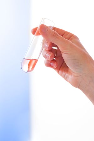 Woman's hand holding test-tube with red liquid