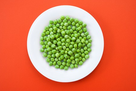 Fresh green peas [pisum sativum] in white plateの写真素材