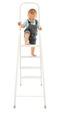 Baby boy's dangerous play: climbing up on white metallic ladderの写真素材