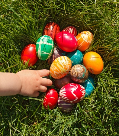 Child hand taking decorated Easter egg from grassの写真素材