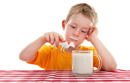 Young kid holding toy cow above big glass cup of milkの写真素材
