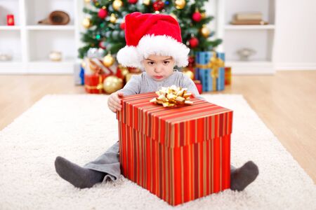 Little boy sitting behind big Christmas present boxの写真素材