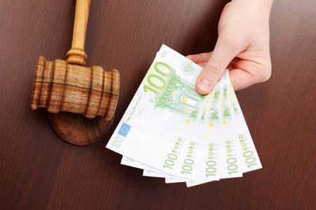 Hand showing money near wooden gavel  Concept of bribe or corruption in justiceの写真素材