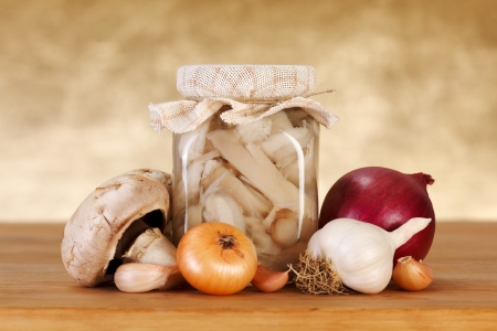 Pickled mushrooms on wooden board with fresh vegetablesの写真素材