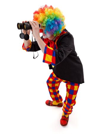 Clown in colorful wig searching; looking through binocularsの写真素材