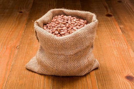 Loose dry pinto beans in burlap sack on wooden board backgroundの写真素材