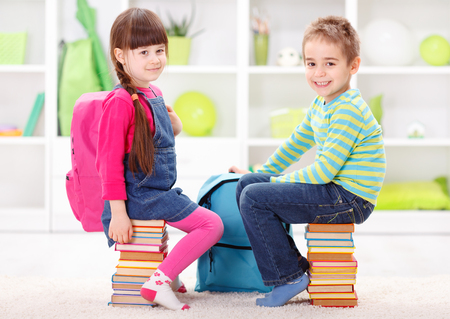 Start of school and learning - little pupils sitting on piles of booksの写真素材