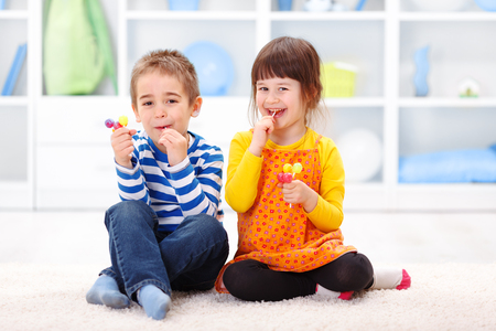Little boy and girl sitting and eating lollipopの写真素材