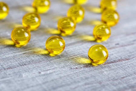 Shiny, small vitamin capsules on wooden backgroundの写真素材