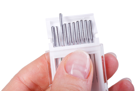 Hand holding set of sewing machine needles on white backgroundの写真素材