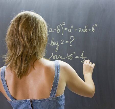 Teacher writing math formulas on blackboard